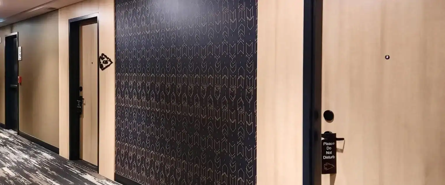 Hotel Hallway Wallpaper Installation and Painting A hotel hallway featuring patterned wallpaper on one side and light wood painted doors.