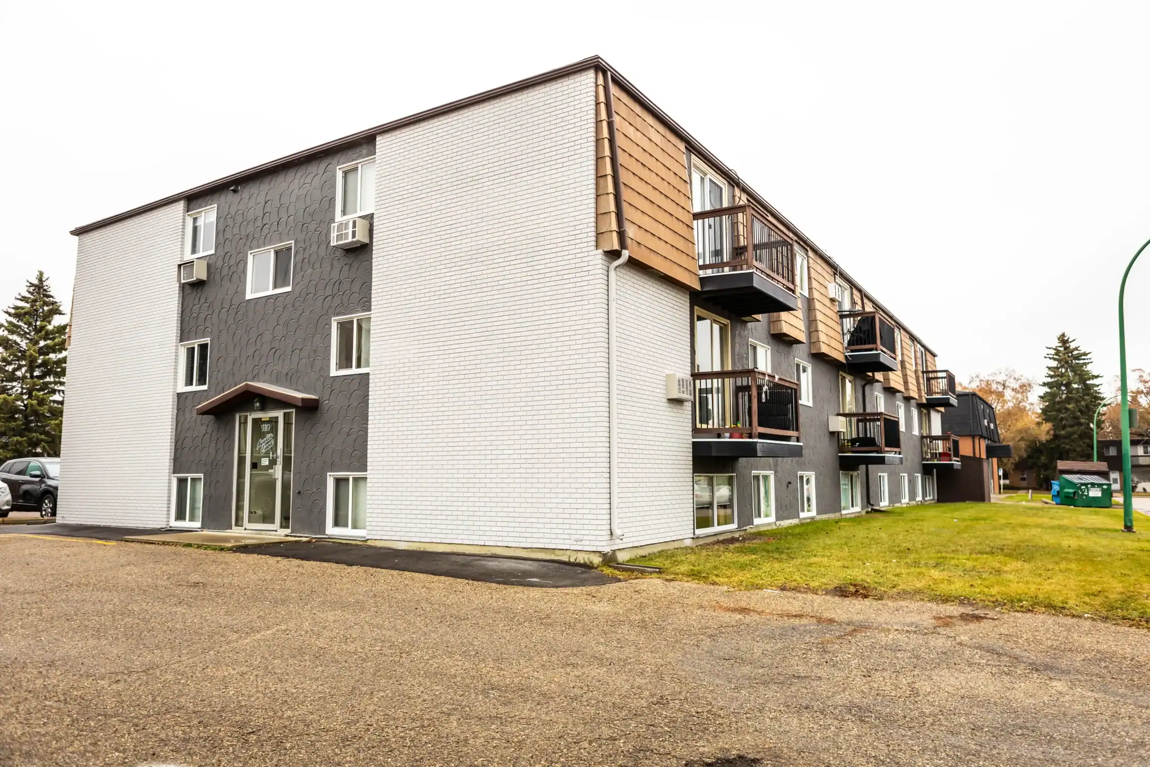 Apartment Building Exterior Painting and Renovation Services Front view of an older multi story apartment building with dark gray and white painted exterior walls.