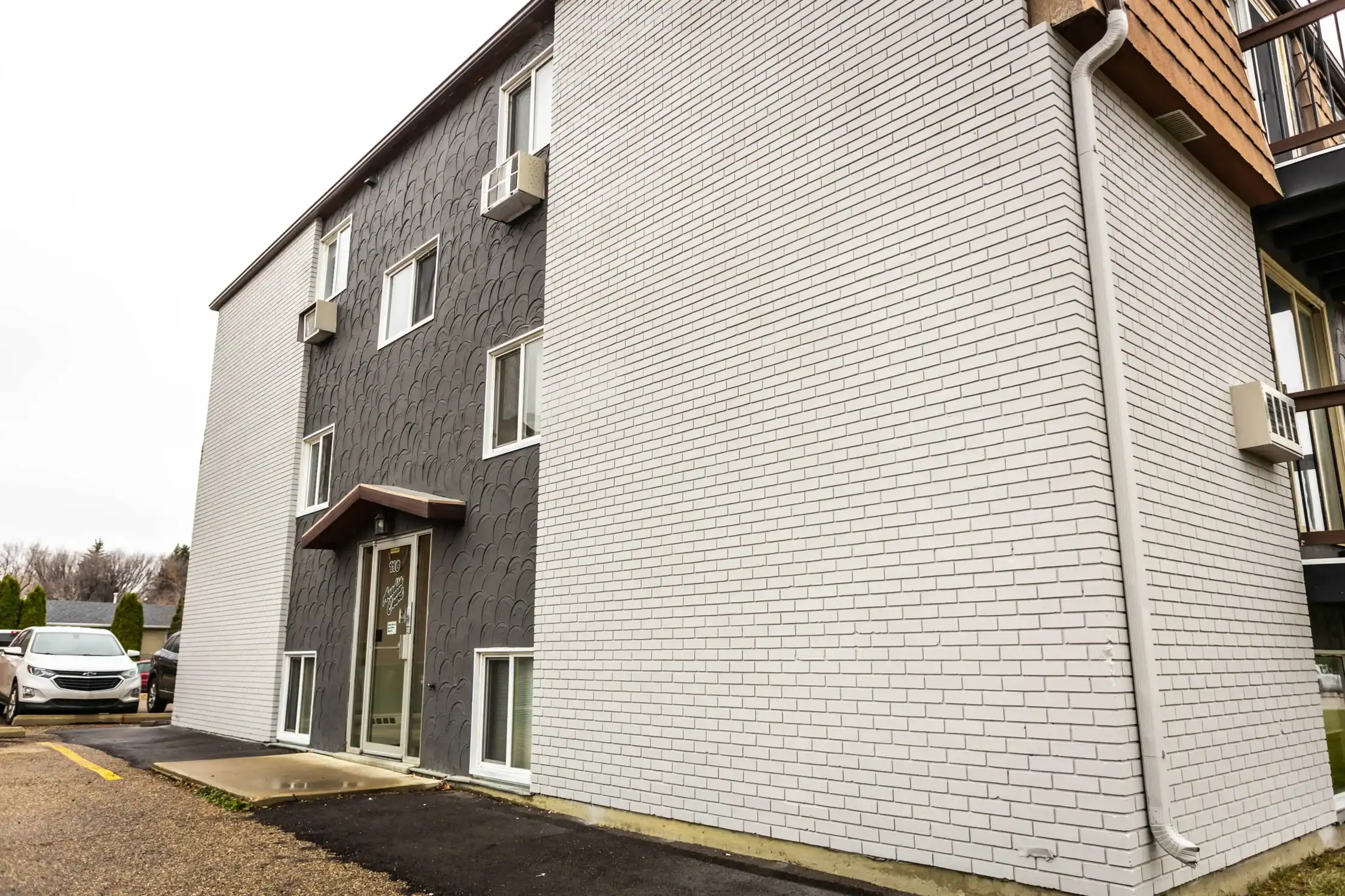 Multi Family Exterior Painting with Brick and Siding Finishes Side view of an apartment building showcasing a mix of dark textured and white painted brick exterior.