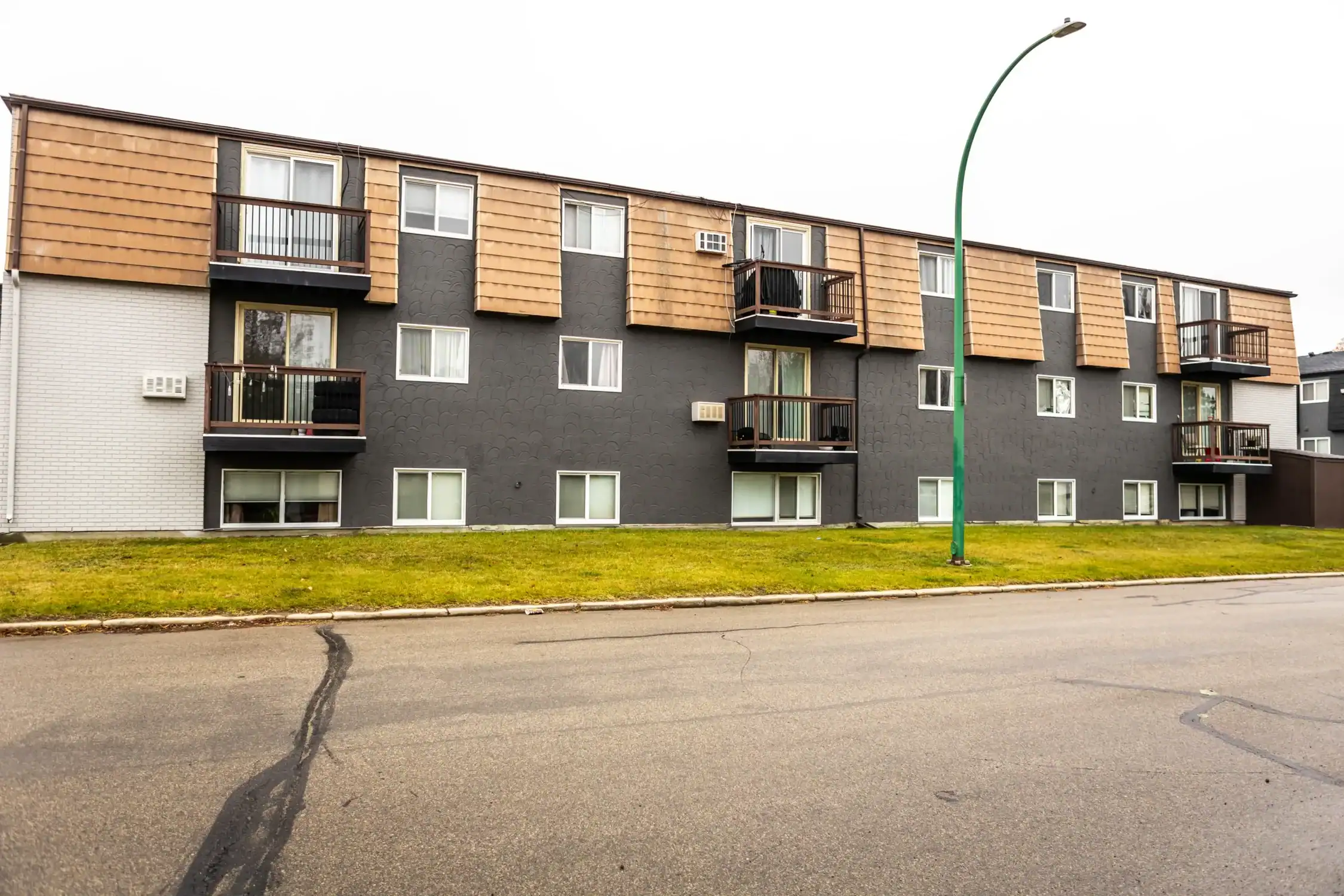Comprehensive Apartment Complex Exterior Painting Solutions Wide exterior shot of a multi story apartment building with dark gray and white sections and balconies.