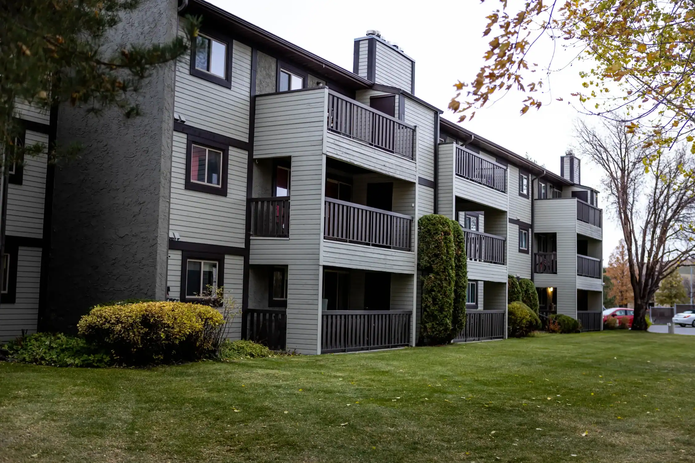 Exterior Painting for Multi Family Residential Buildings Side view of a multi story residential building with balconies, light gray siding, and dark trim.