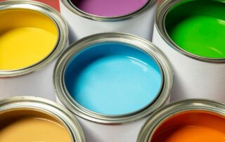 Several open paint cans display a vibrant array of colors, including yellow, purple, blue, green, and orange.