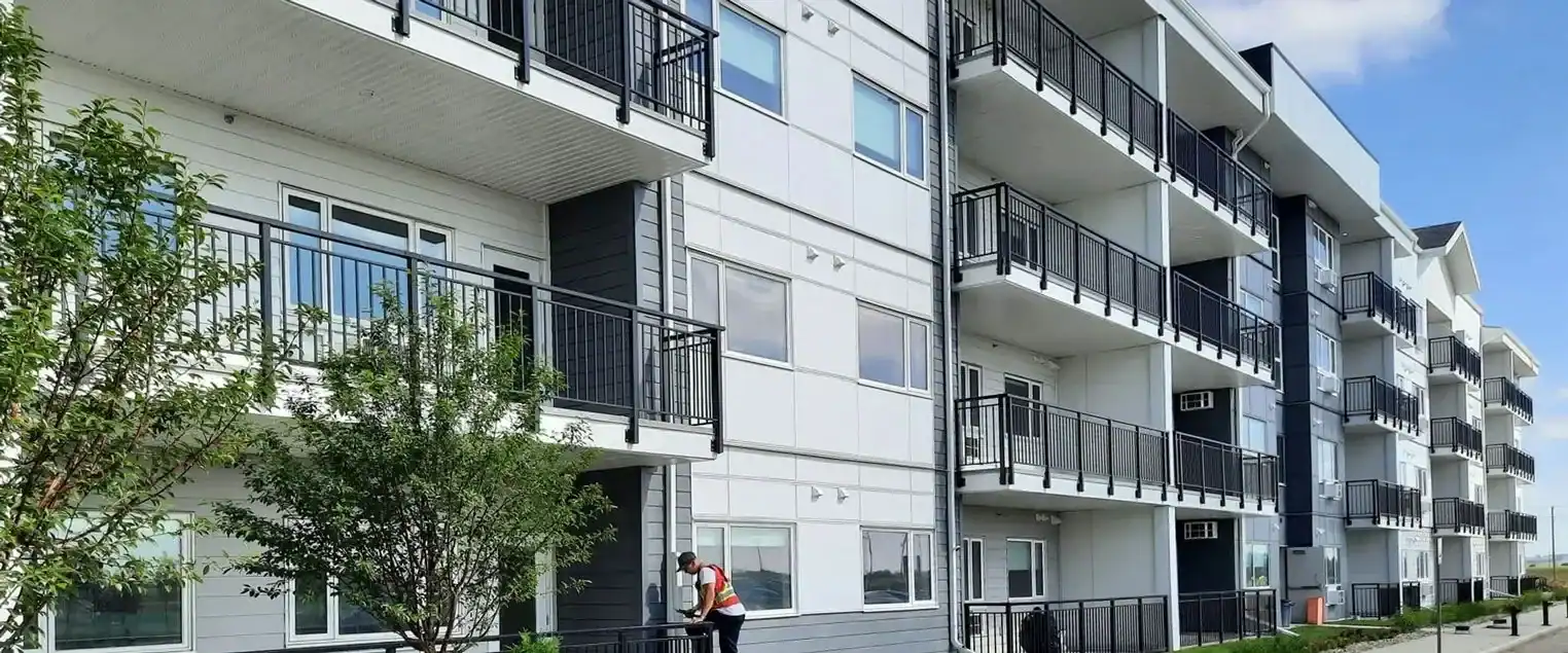 Professional Exterior Painting for Multi Family Residential Buildings Exterior view of a large multi family apartment complex with several balconies and light gray siding.