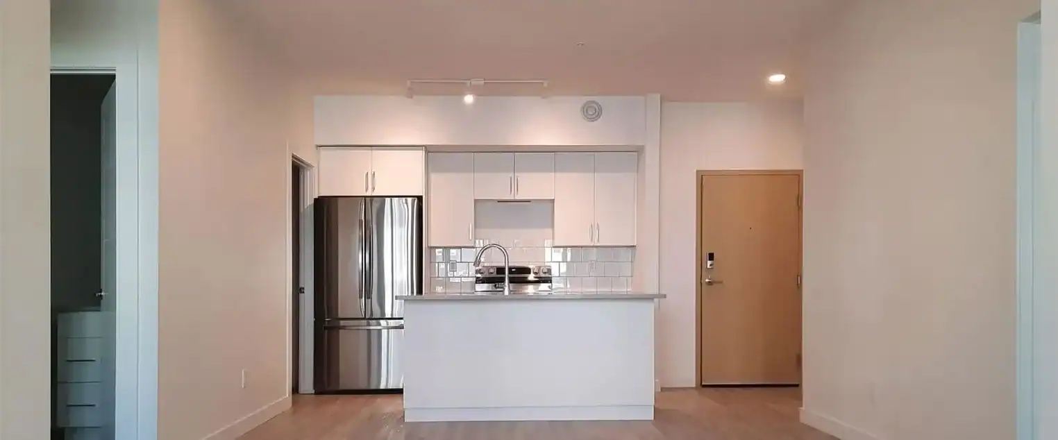 Open Concept Apartment Interior Painting Services Open concept apartment kitchen and living area, featuring white cabinets and freshly painted light walls.