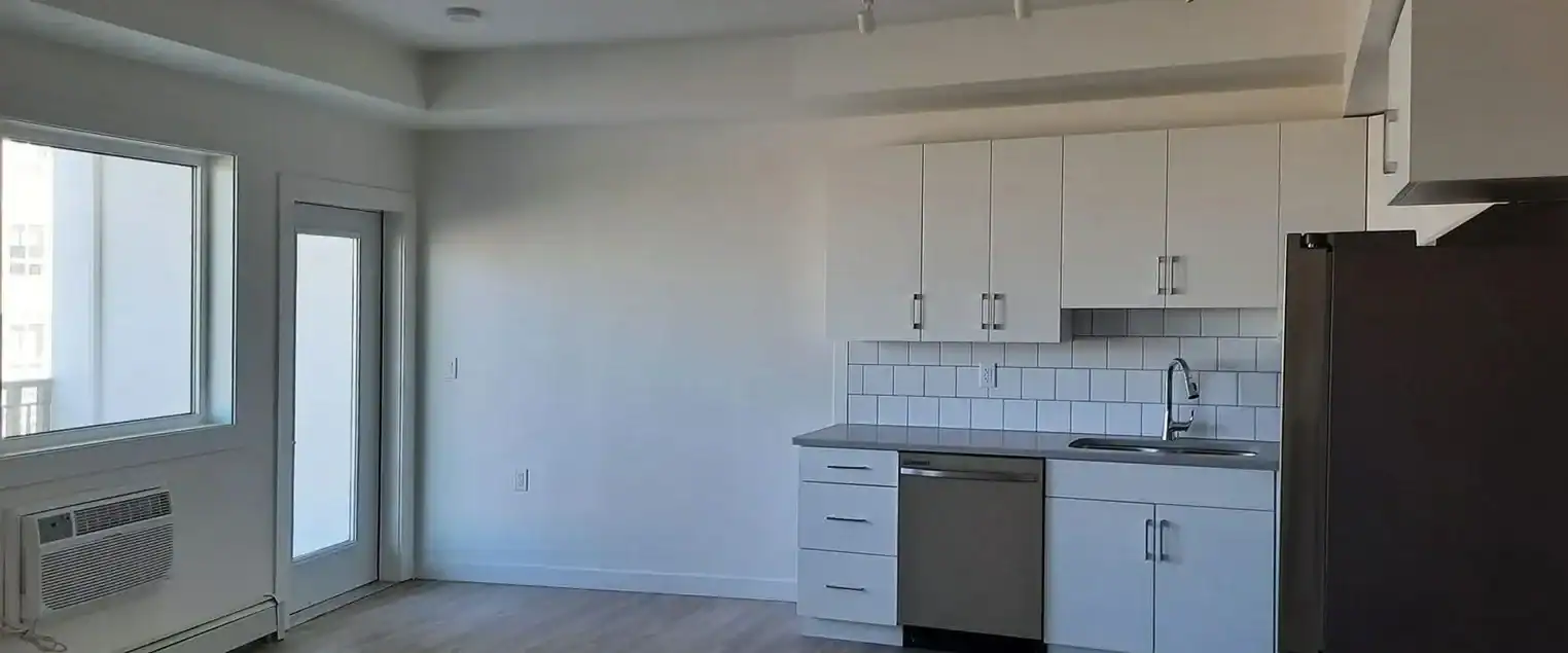 Apartment Interior Painting for Kitchens and Living Areas Modern apartment kitchen with white cabinets and light painted walls, extending to an adjacent living space.