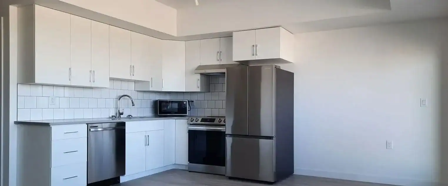 Apartment Kitchen Painting and Cabinet Refinishing Modern apartment kitchen with white cabinets, stainless steel appliances, and light painted walls, ideal for apartment painting.
