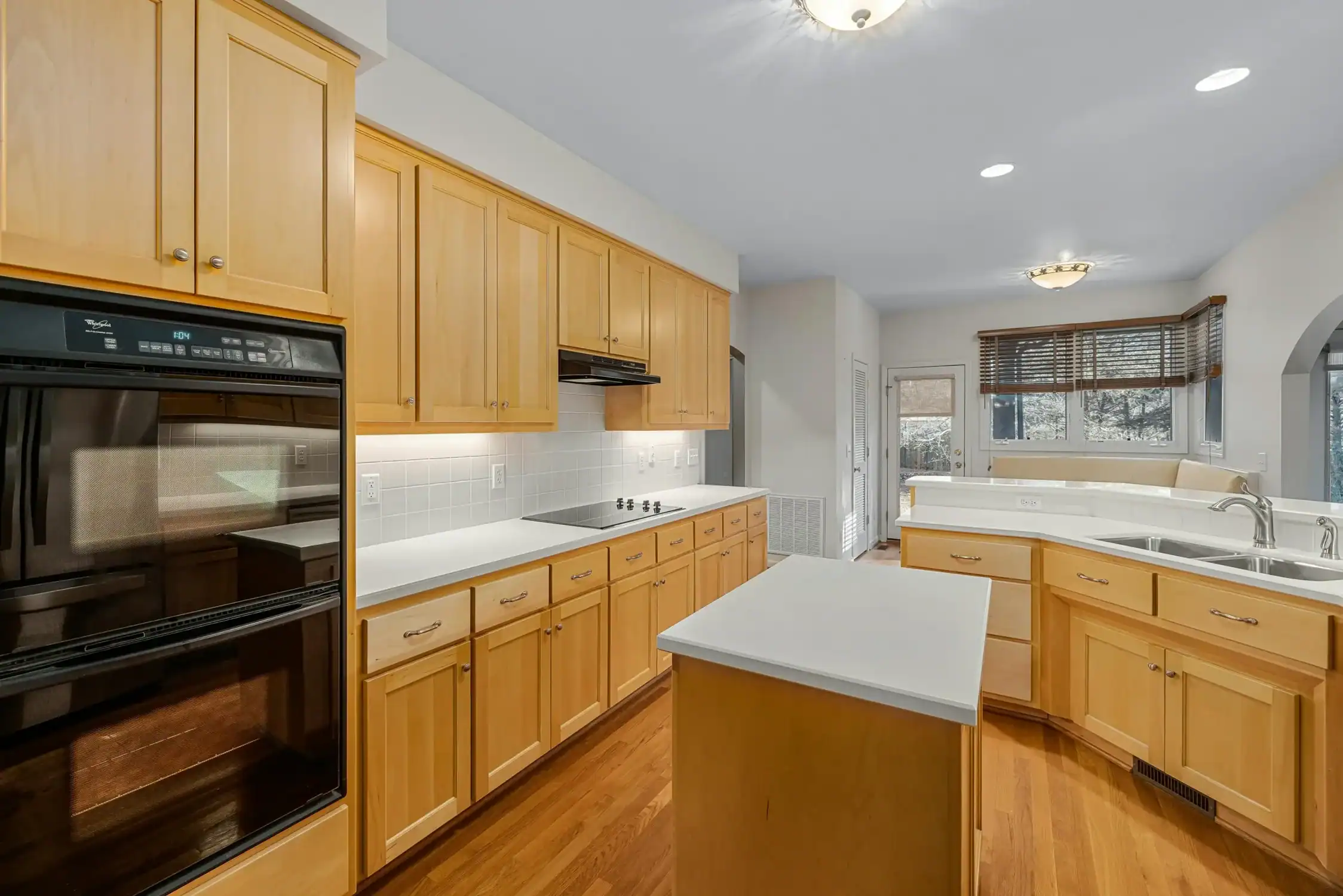 Kitchen Cabinet Painting for Remodel and Renovation Kitchen with light wood cabinets, white countertops, and a central island, ideal for cabinet painting and renovation.