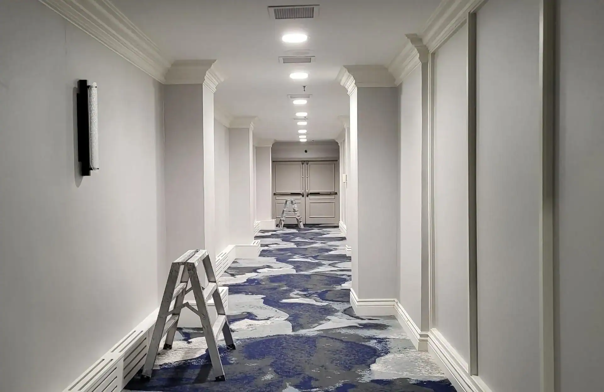 Commercial Hallway Interior Painting A long commercial hallway with freshly painted light grey walls and white trim.