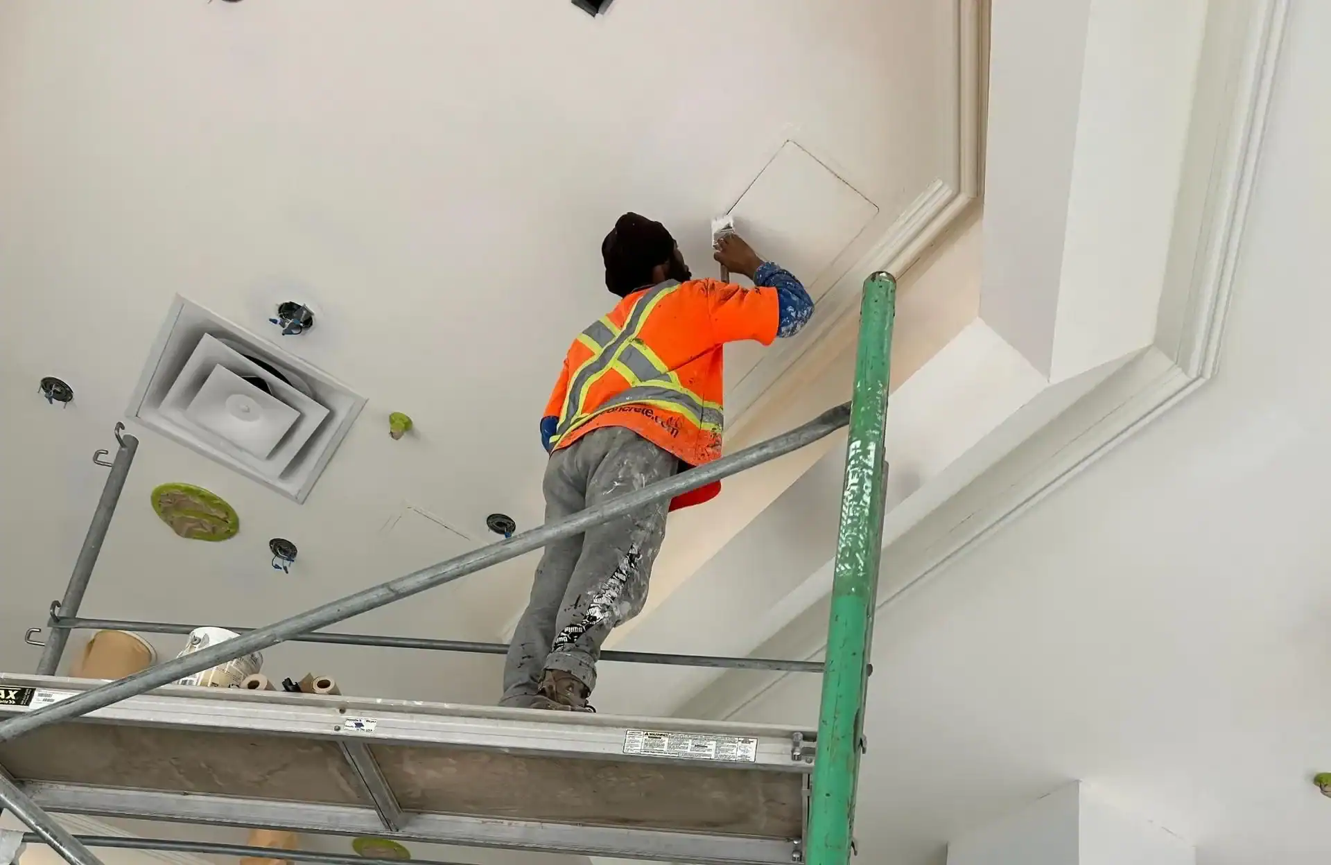 Commercial Ceiling and Trim Painting A painter on scaffolding meticulously painting the intricate ceiling trim in a commercial space.