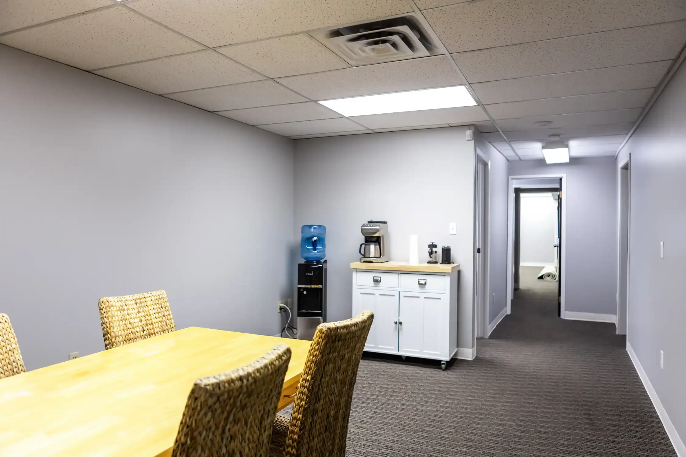 Office Break Room Interior Painting A clean office break room with grey walls, a coffee station, and a water cooler.