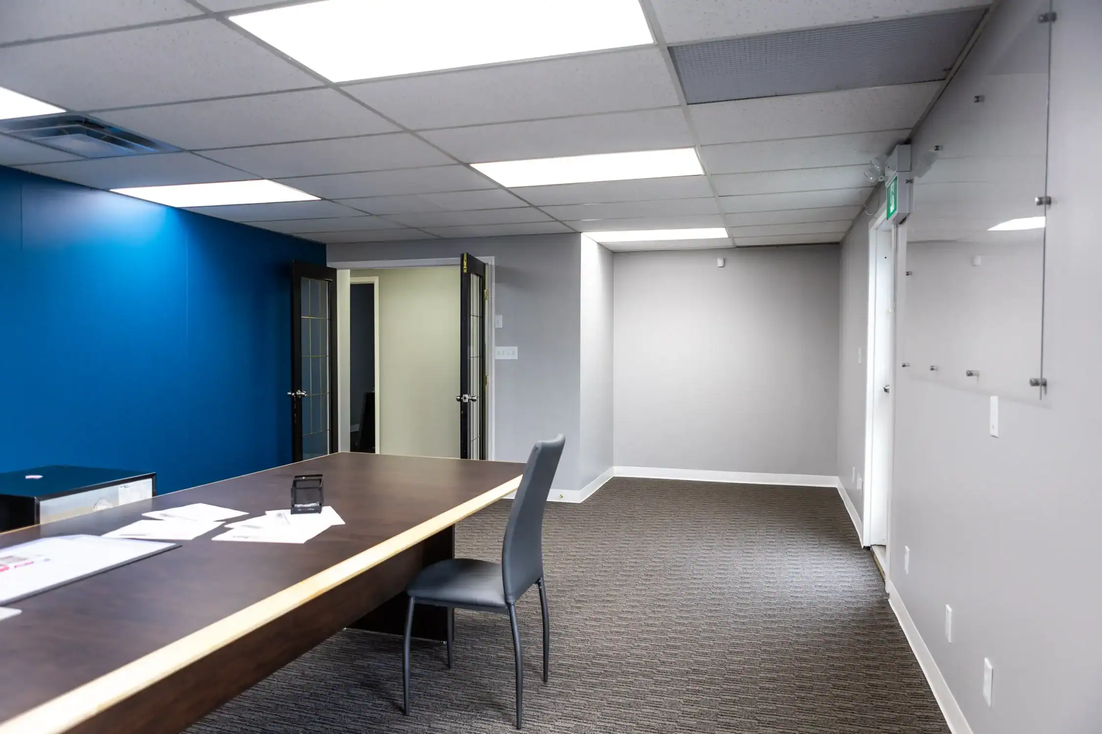 Office Interior Painting with Accent Wall A modern office interior featuring a vibrant blue accent wall and light grey painted walls.