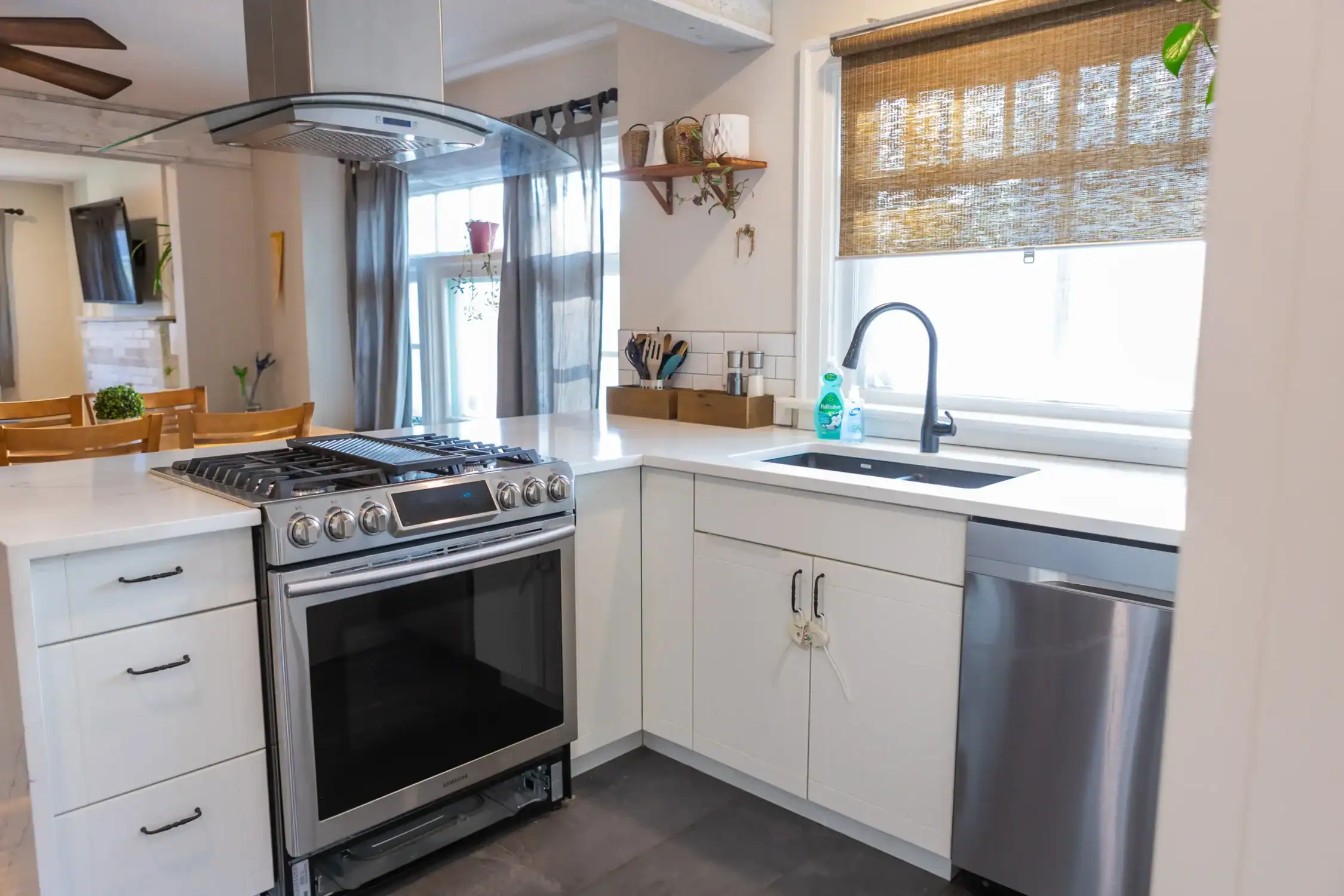 Kitchen Cabinet and Wall Painting Services Contemporary kitchen with white cabinets, a sink, dishwasher, and a stovetop island, displaying clean interior painting.