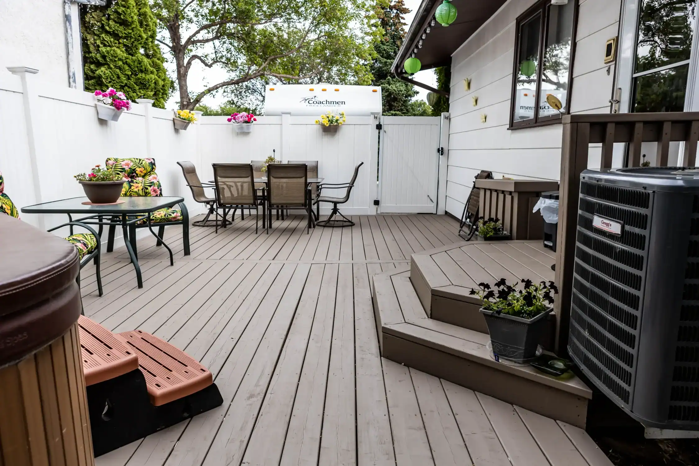 Professional Deck Staining and Outdoor Wood Protection Services A spacious outdoor wooden deck stained in a neutral gray, featuring patio furniture and a hot tub.
