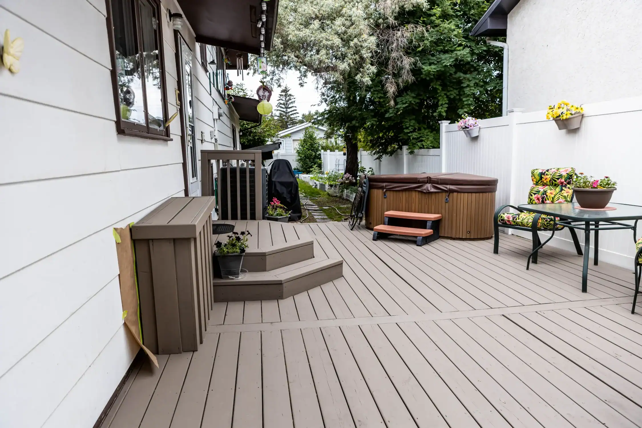 Expert Deck Staining for Enhanced Outdoor Living Spaces View of a freshly stained wooden deck with steps leading to a hot tub and outdoor seating area.