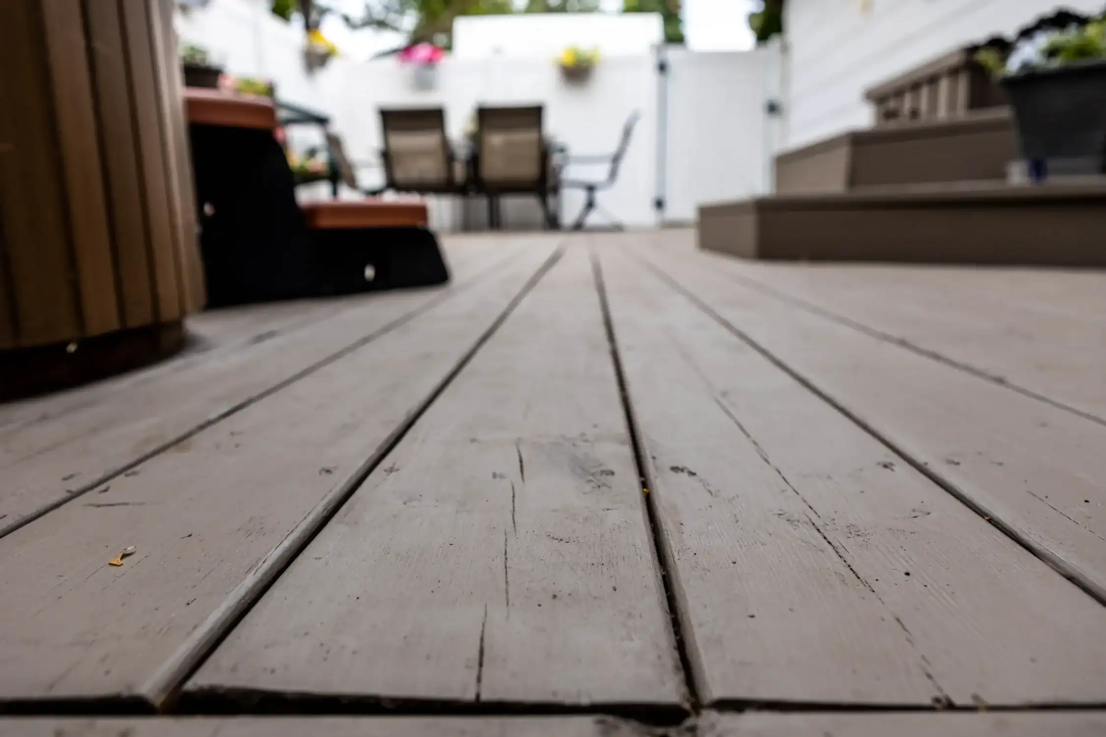 Detailed Deck Staining and Wood Finishing for Durability Close up of weathered wooden deck boards with a gray stain, highlighting texture and finish.