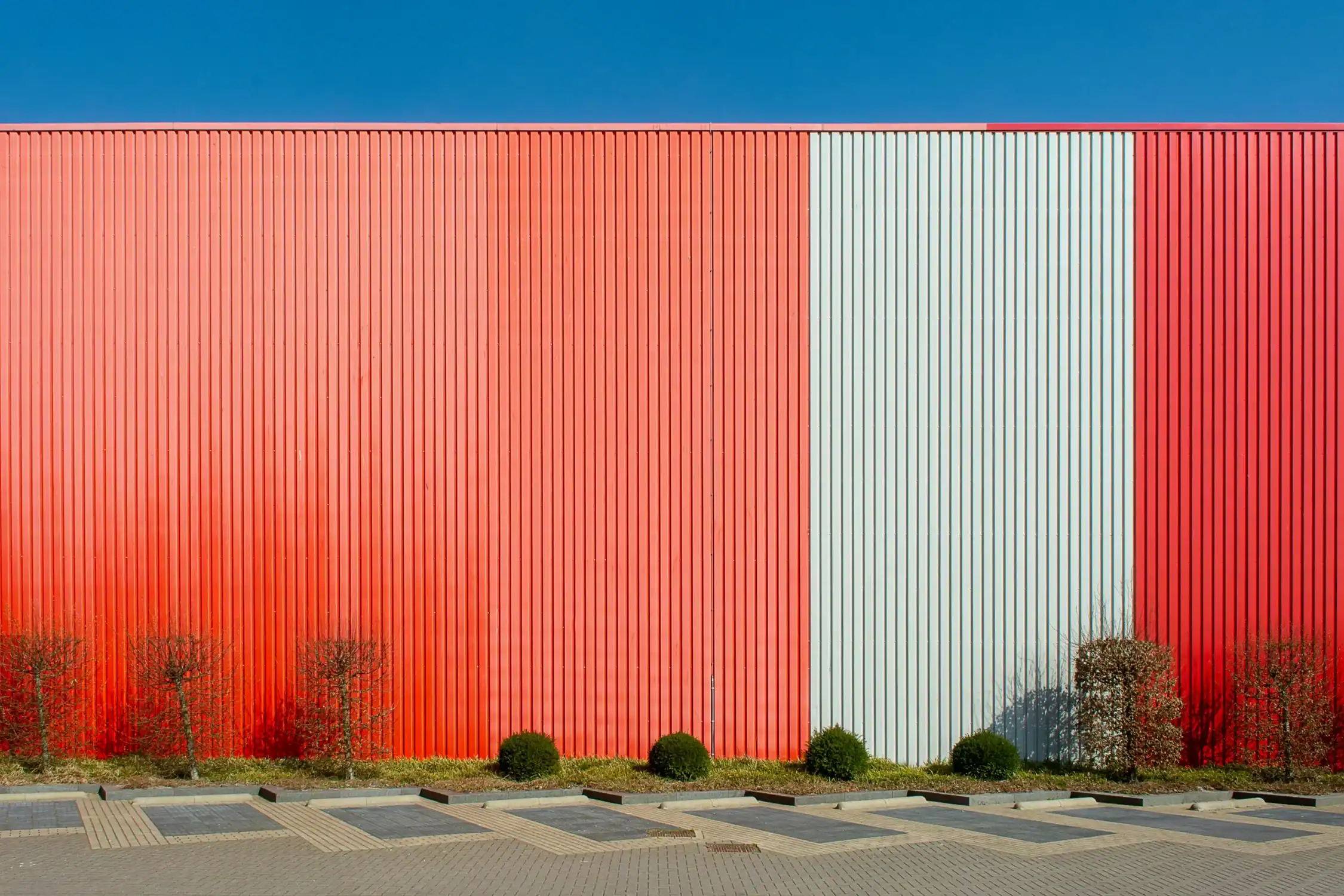 Large Commercial Building Exterior Painting A large commercial building exterior with corrugated metal siding painted red and white.