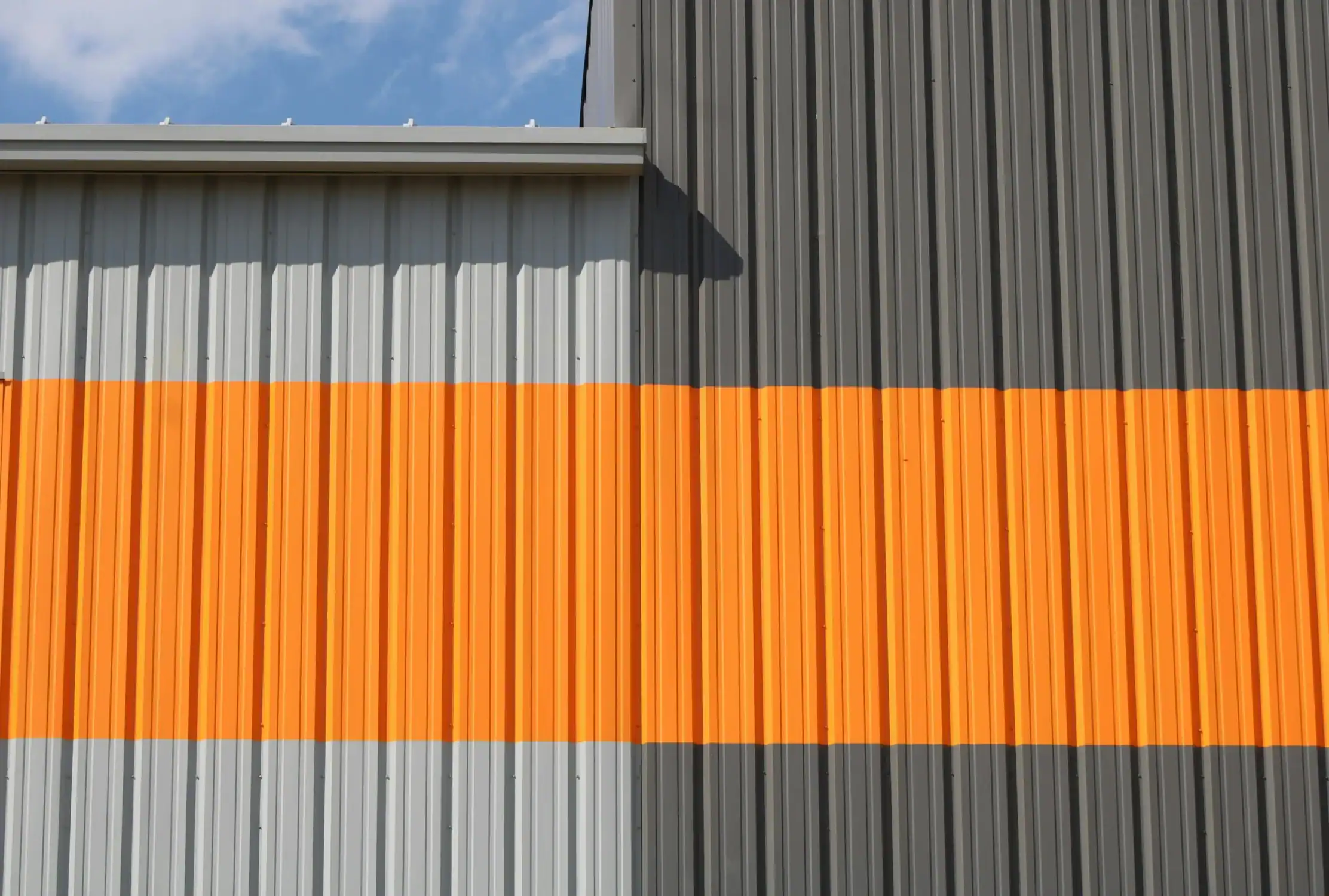 Commercial Exterior Accent Painting on Metal Siding Corrugated metal siding on a commercial building with a bold orange accent stripe.