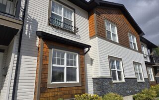 A multi story residential building showcasing a mix of white siding, wood shingles, and stone veneer.