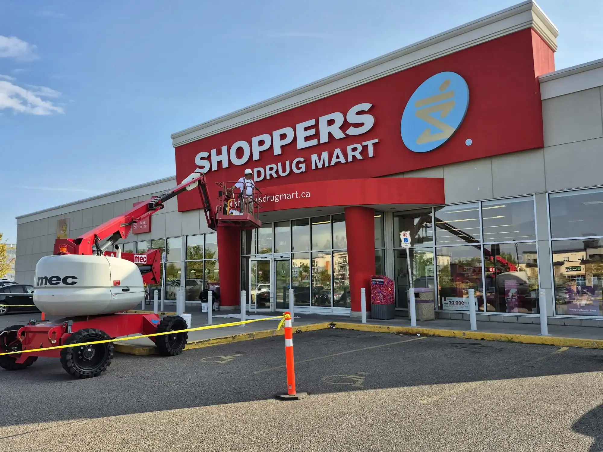Large Scale Commercial Exterior Painting Project An exterior view of a commercial store with a painter on a lift working on the facade.