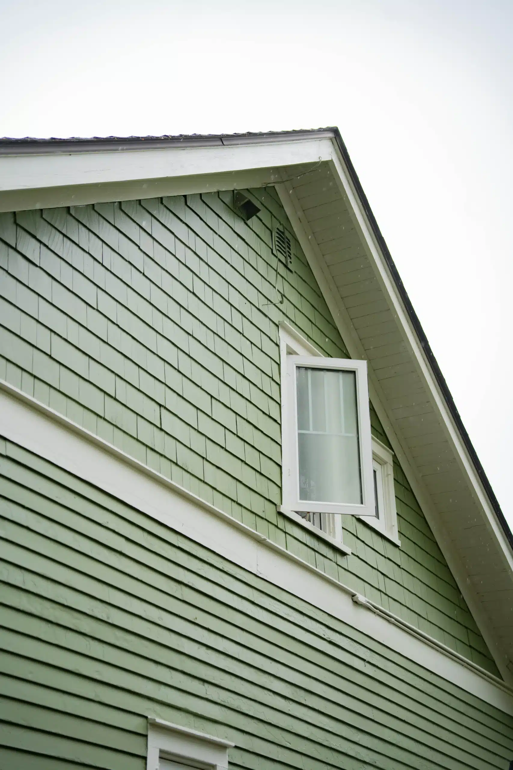 Residential House Exterior with Green Siding and White Trim Close up of a residential house exterior featuring green shingle and plank siding with crisp white trim.